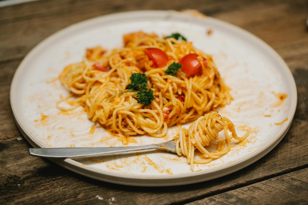 Spaghetti with tomato sauce, cherry tomatoes, and parsley with a fork